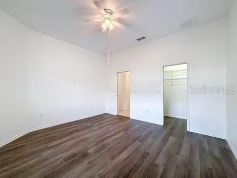 9237 Penelope Dr, Weeki Wachee, FL 34613 - unfurnished bedroom featuring a closet, a spacious closet, ceiling fan, dark wood-type flooring, and visible vents