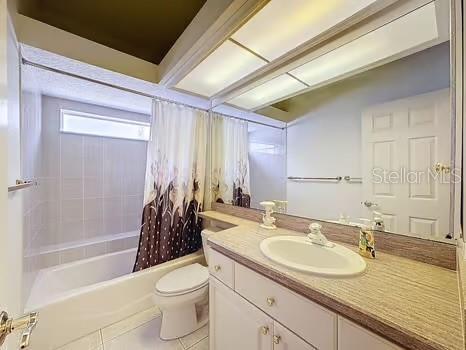 9237 Penelope Dr, Weeki Wachee, FL 34613 - full bath with shower / bath combo with shower curtain, toilet, vanity, and tile patterned floors