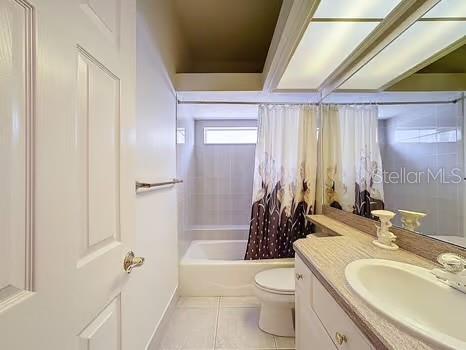 9237 Penelope Dr, Weeki Wachee, FL 34613 - full bath with  shower combination, toilet, baseboards, tile patterned flooring, and vanity