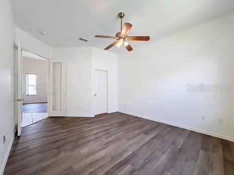 9237 Penelope Dr, Weeki Wachee, FL 34613 - spare room featuring baseboards, visible vents, a ceiling fan, and dark wood-style floors