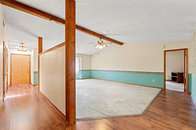 3029 Harrow Rd, Spring Hill, FL 34606 - unfurnished living room with ceiling fan, lofted ceiling with beams, a textured ceiling, baseboards, and wood finished floors