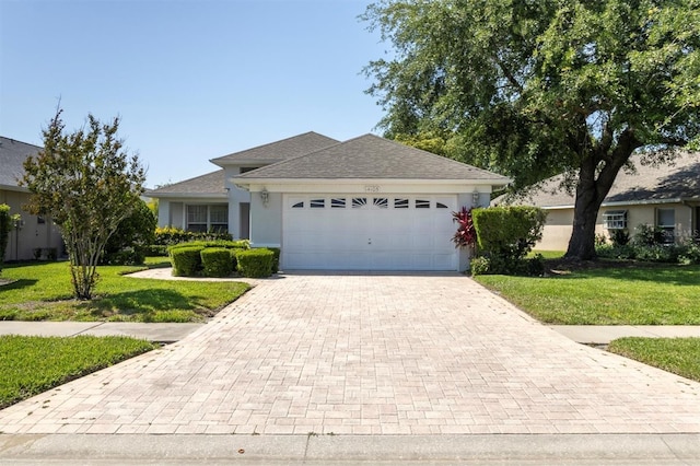 14105 Agua Clara Dr, Hudson, FL 34667 - ranch-style home featuring a front lawn, a garage, decorative driveway, stucco siding, and a shingled roof
