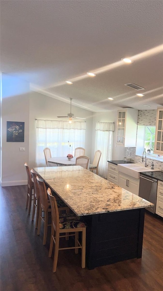14105 Agua Clara Dr, Hudson, FL 34667 - kitchen with stainless steel dishwasher, glass insert cabinets, white cabinetry, light stone counters, and dark wood-style floors