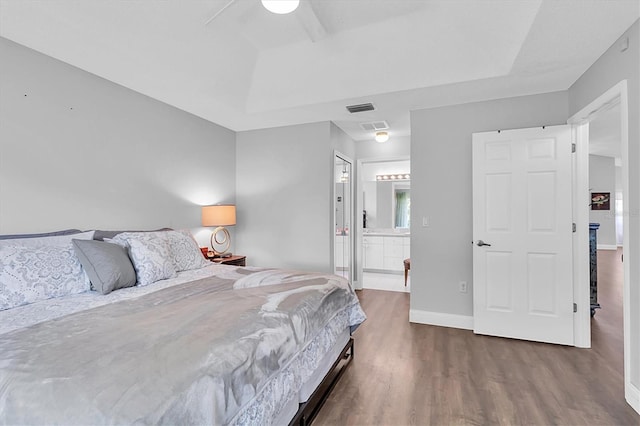 14105 Agua Clara Dr, Hudson, FL 34667 - bedroom featuring wood finished floors, a tray ceiling, ensuite bath, and ceiling fan