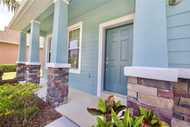 entrance to property featuring a porch and stone siding