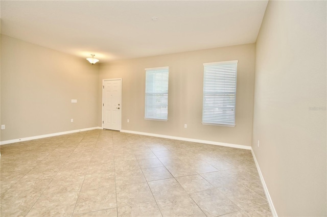 empty room featuring baseboards and light tile patterned flooring