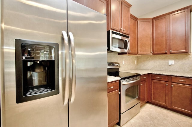 kitchen featuring backsplash, appliances with stainless steel finishes, brown cabinets, light stone countertops, and light tile patterned floors