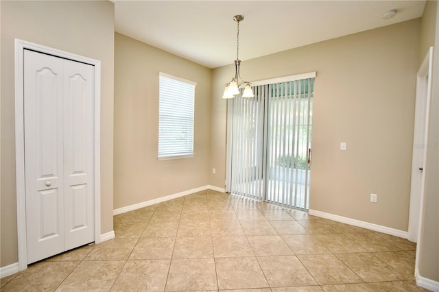 spare room featuring a chandelier, baseboards, and light tile patterned floors