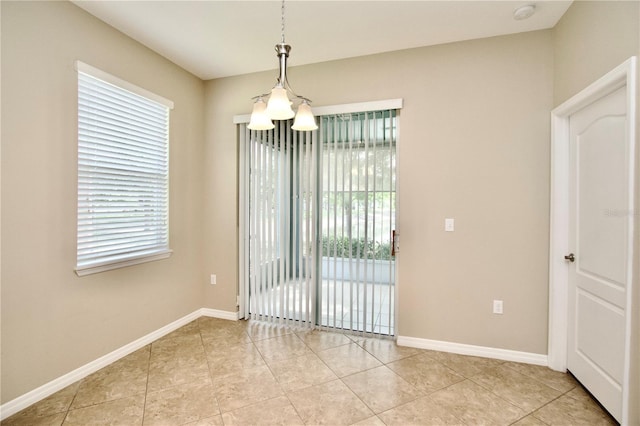unfurnished room featuring baseboards, a chandelier, and light tile patterned floors