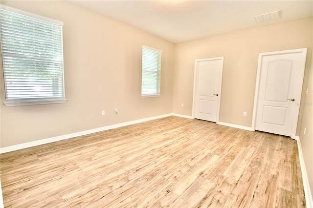 empty room with wood finished floors, a wealth of natural light, and baseboards