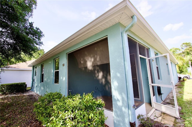 view of side of property with a sunroom and stucco siding