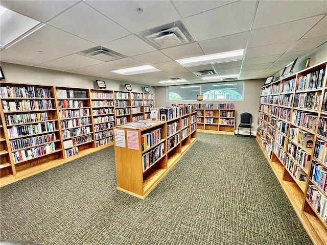 miscellaneous room with bookshelves, a paneled ceiling, visible vents, and carpet floors