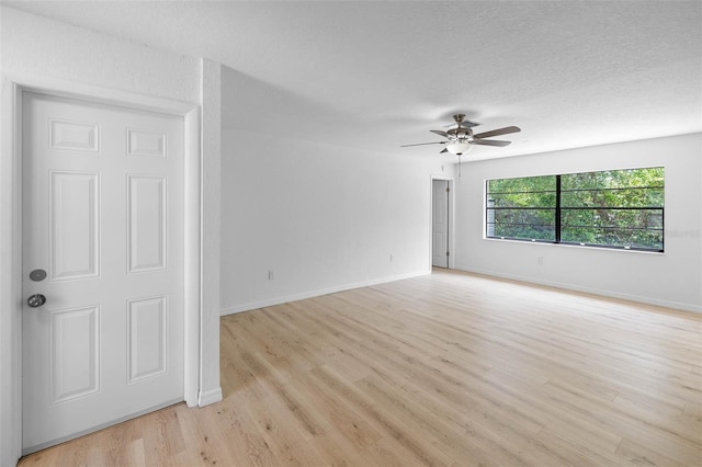 unfurnished room with a ceiling fan, baseboards, a textured ceiling, and light wood-style floors