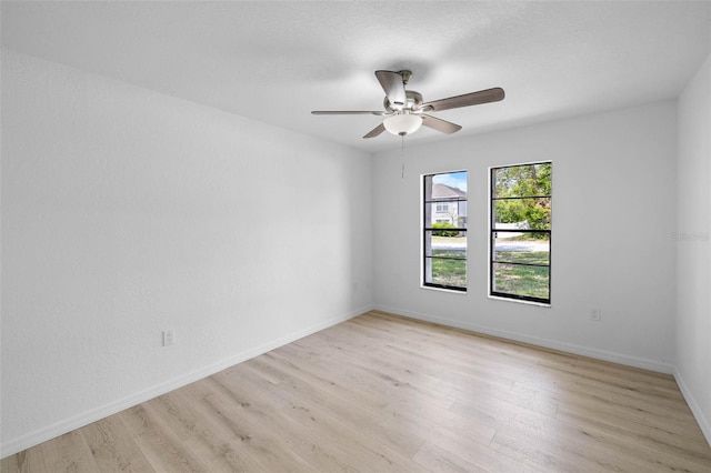spare room featuring baseboards, a ceiling fan, and light wood-style flooring