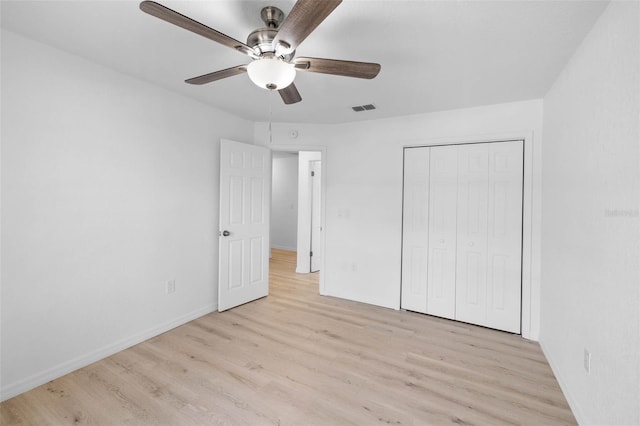 unfurnished bedroom with baseboards, wood finished floors, visible vents, and a closet