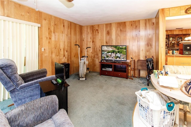 living area featuring carpet floors, a ceiling fan, and wooden walls