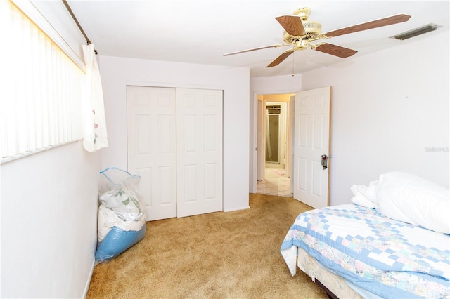 bedroom with a ceiling fan, visible vents, light carpet, and a closet
