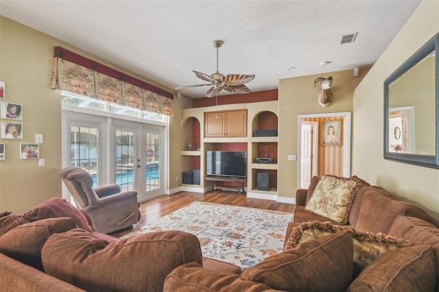 18502 Winding Oaks Blvd, Hudson, FL 34667 - living room featuring visible vents, wood finished floors, built in shelves, french doors, and a ceiling fan