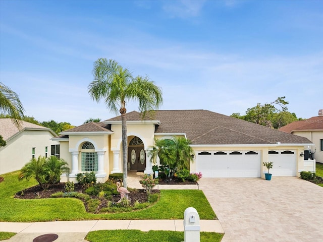 view of front of property with an attached garage, decorative driveway, roof with shingles, and stucco siding
