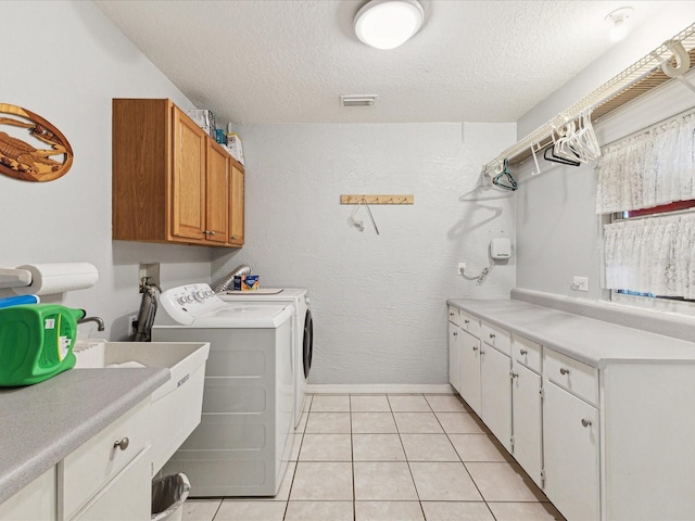 clothes washing area featuring cabinet space, separate washer and dryer, a textured ceiling, and visible vents