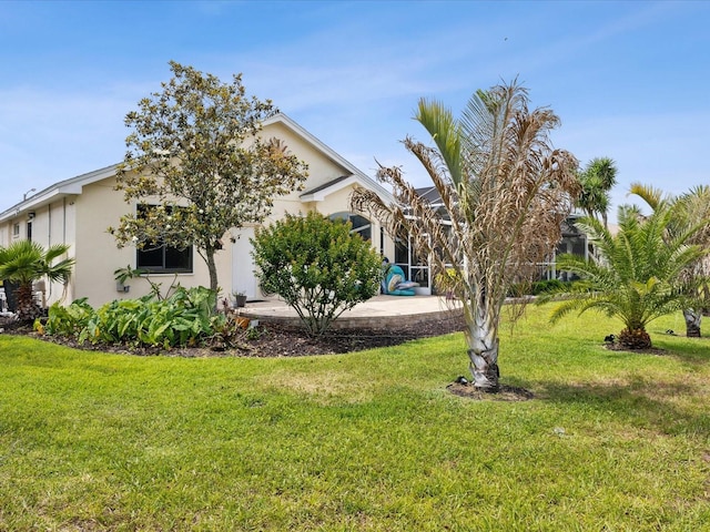 exterior space with a lanai, stucco siding, a front lawn, and a patio