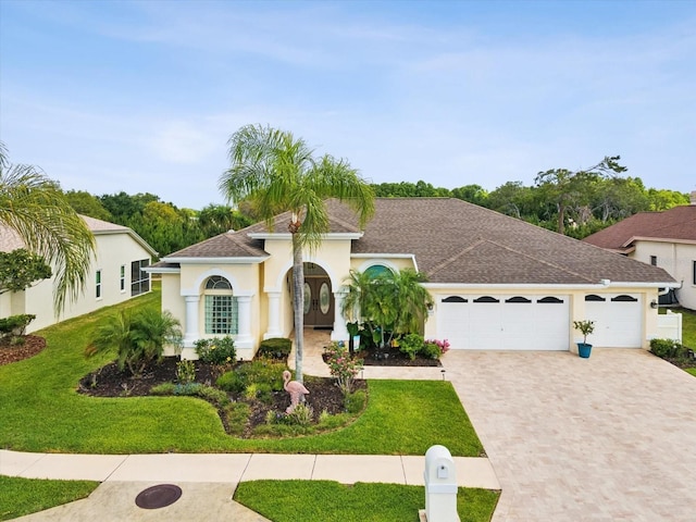 mediterranean / spanish home with an attached garage, stucco siding, driveway, and a front yard