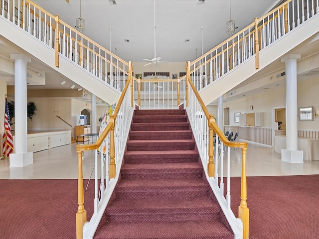 stairway with carpet, ceiling fan, and a high ceiling