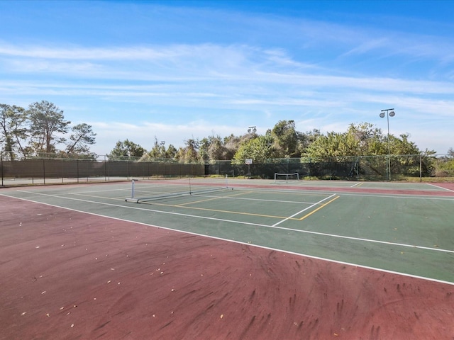 view of tennis court featuring community basketball court and fence
