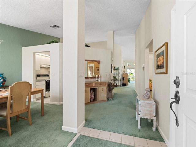 interior space with a textured ceiling, visible vents, lofted ceiling, and carpet