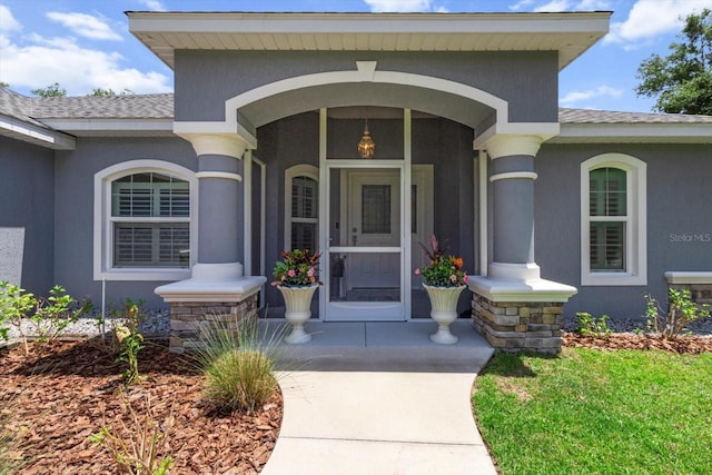 doorway to property featuring a shingled roof, stucco siding, and a porch
