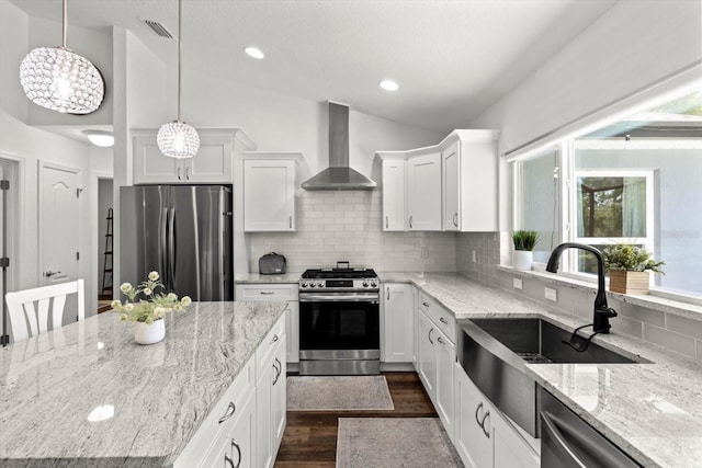kitchen with visible vents, lofted ceiling, wall chimney range hood, a sink, and stainless steel appliances