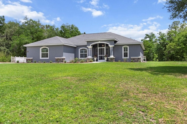 view of front facade with a shingled roof, a front yard, and stucco siding
