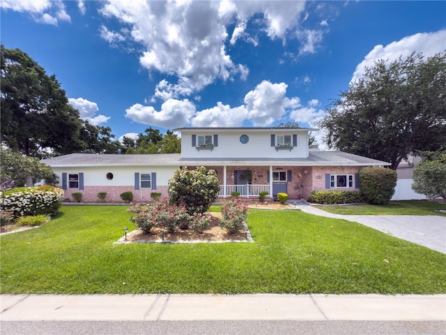 75 N Canal Dr, Palm Harbor, FL 34684 - traditional-style home featuring a porch, a front lawn, and brick siding