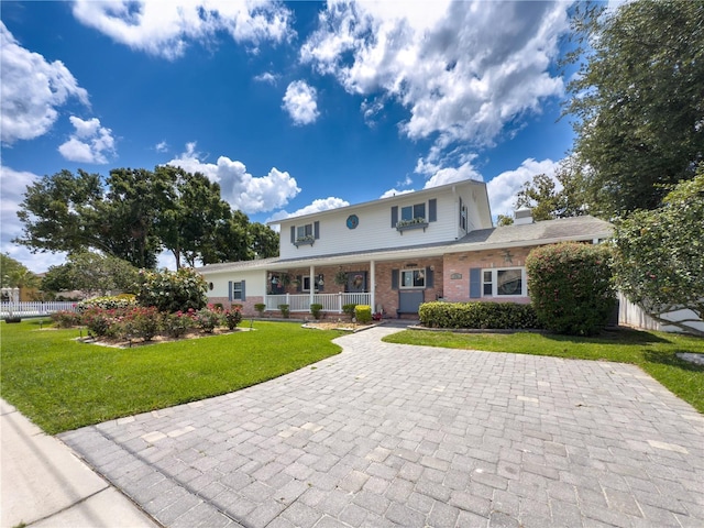 75 N Canal Dr, Palm Harbor, FL 34684 - view of front of home featuring a chimney, a porch, a front lawn, and brick siding