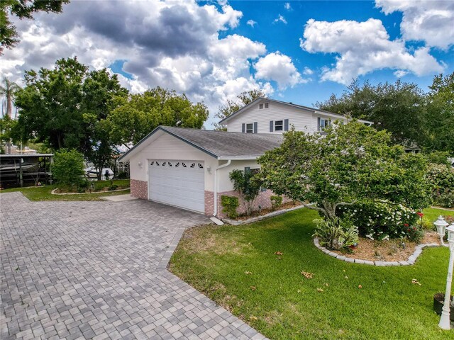75 N Canal Dr, Palm Harbor, FL 34684 - view of front of property with a shingled roof, an attached garage, a front lawn, brick siding, and decorative driveway