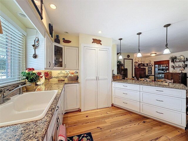 75 N Canal Dr, Palm Harbor, FL 34684 - kitchen with a peninsula, white cabinetry, a sink, and light wood-style floors