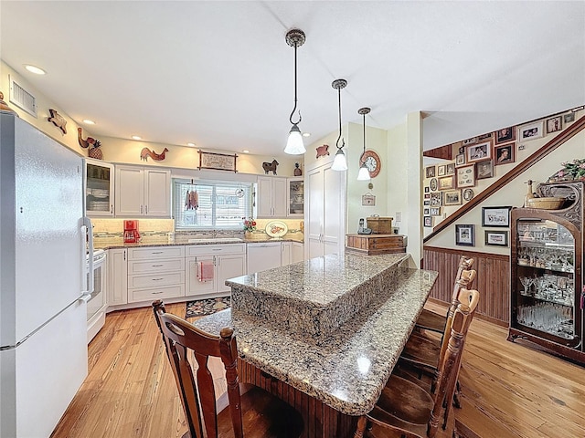 75 N Canal Dr, Palm Harbor, FL 34684 - kitchen featuring light wood-style floors, a kitchen breakfast bar, white cabinets, and white appliances