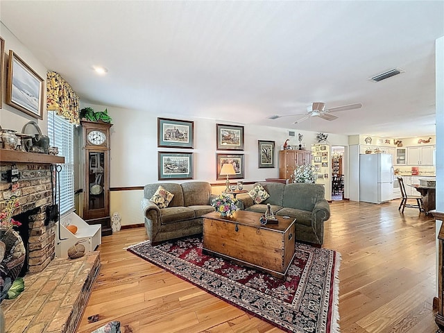 75 N Canal Dr, Palm Harbor, FL 34684 - living room featuring visible vents, a fireplace, baseboards, a ceiling fan, and light wood-style flooring