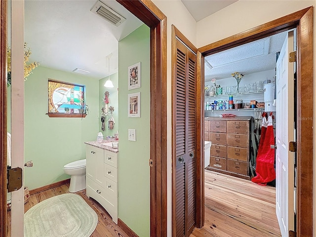 75 N Canal Dr, Palm Harbor, FL 34684 - bathroom with visible vents, a closet, vanity, wood finished floors, and toilet