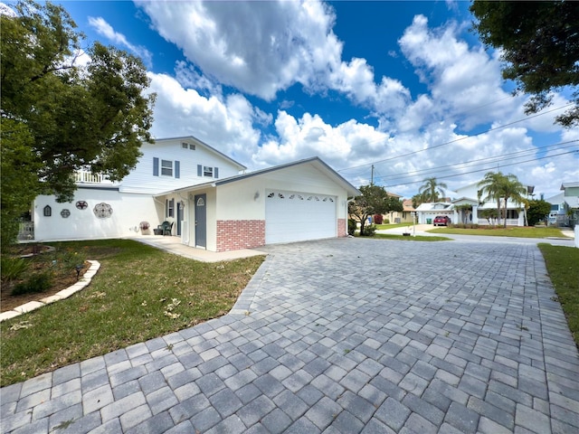 75 N Canal Dr, Palm Harbor, FL 34684 - view of front of house featuring an attached garage, a front lawn, decorative driveway, and brick siding