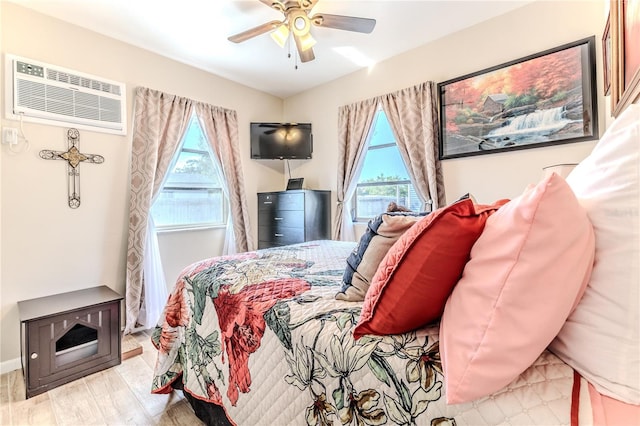 bedroom featuring multiple windows, a ceiling fan, a wall mounted air conditioner, and wood finished floors