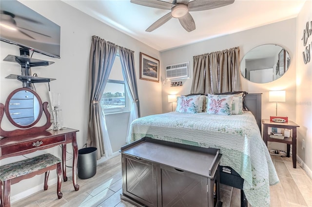 bedroom with an AC wall unit, baseboards, ceiling fan, and light wood-style flooring