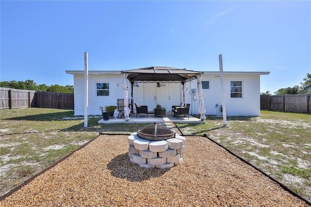 rear view of house featuring a lawn, a fenced backyard, stucco siding, a patio area, and a gazebo