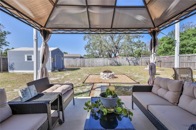 view of patio / terrace with a storage shed, a gazebo, a fenced backyard, and an outdoor living space with a fire pit