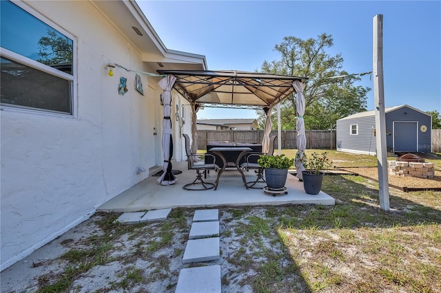view of yard featuring an outdoor structure, fence, a patio area, a gazebo, and a storage shed