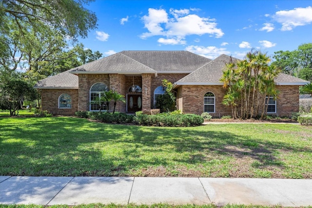 888 Royal Birkdale Dr, Tarpon Springs, FL 34688 - view of front facade featuring brick siding, a shingled roof, and a front lawn