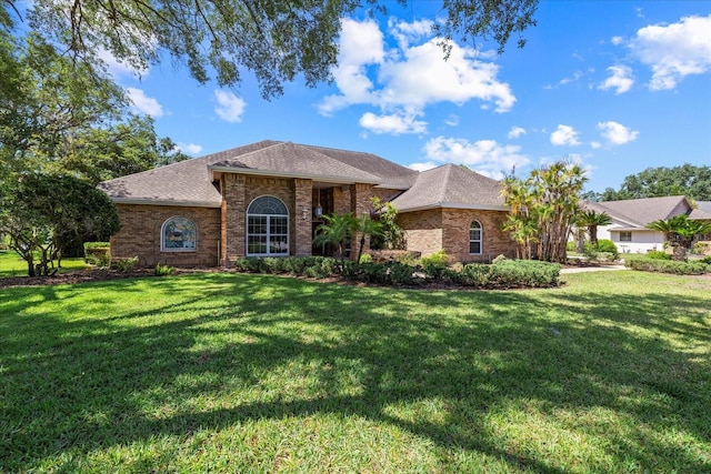 888 Royal Birkdale Dr, Tarpon Springs, FL 34688 - view of front of home with brick siding, a front yard, and roof with shingles