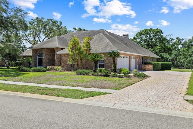 888 Royal Birkdale Dr, Tarpon Springs, FL 34688 - view of front of home with driveway, a chimney, a front yard, brick siding, and an attached garage