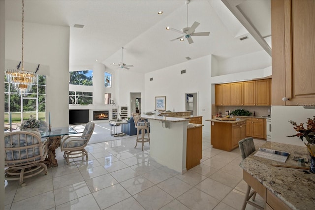888 Royal Birkdale Dr, Tarpon Springs, FL 34688 - kitchen with a center island, light stone countertops, high vaulted ceiling, ceiling fan with notable chandelier, and open floor plan