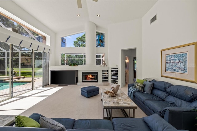 888 Royal Birkdale Dr, Tarpon Springs, FL 34688 - living room with visible vents, a glass covered fireplace, ceiling fan, high vaulted ceiling, and carpet